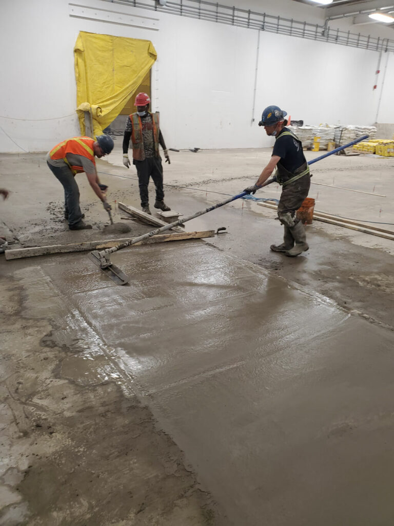 photo of ESS staff leveling fresh concrete in an Edmonton warehouse