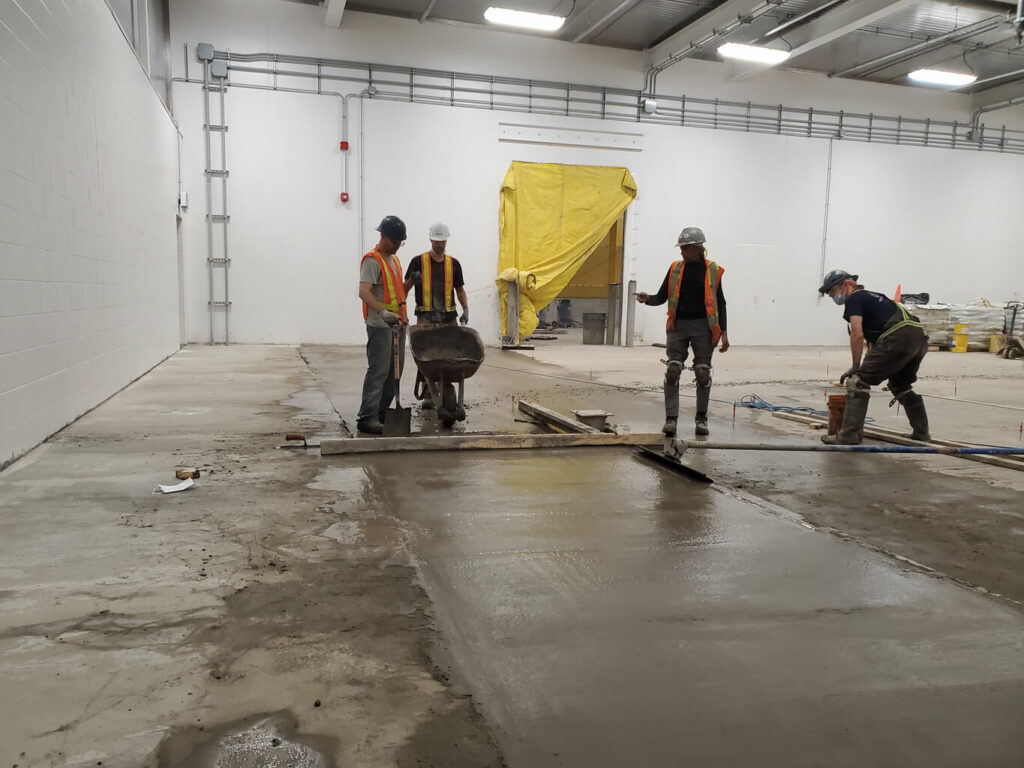 photo of ESS staff leveling fresh concrete in an Edmonton warehouse