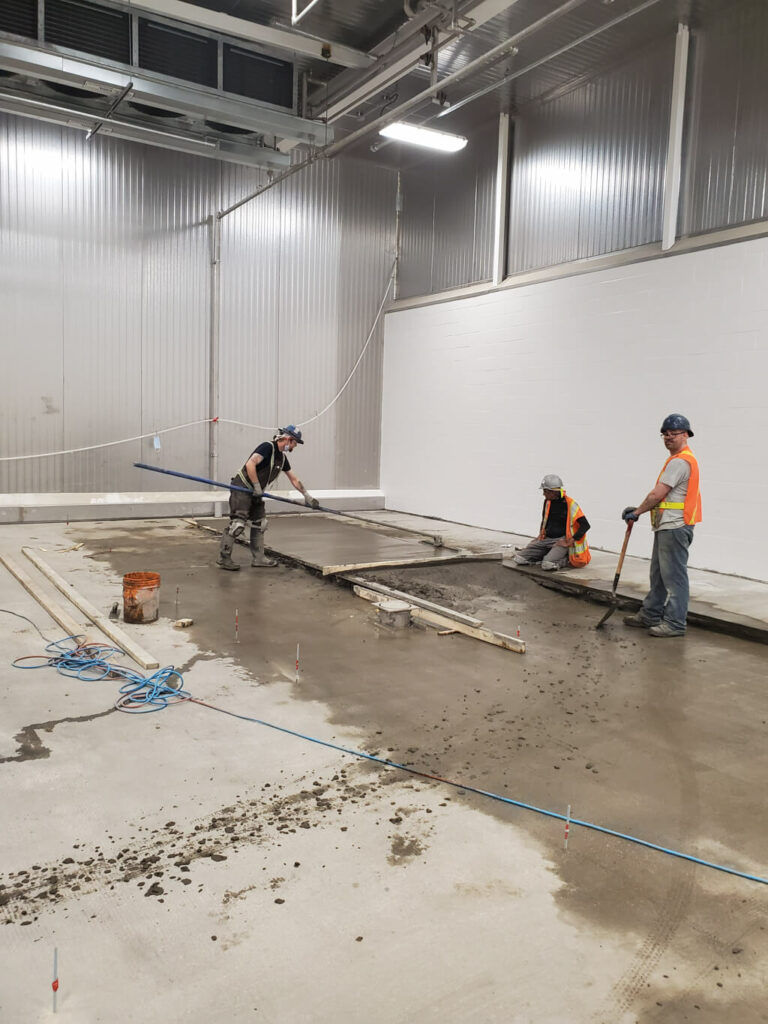 photo of ESS staff leveling fresh concrete in an Edmonton warehouse