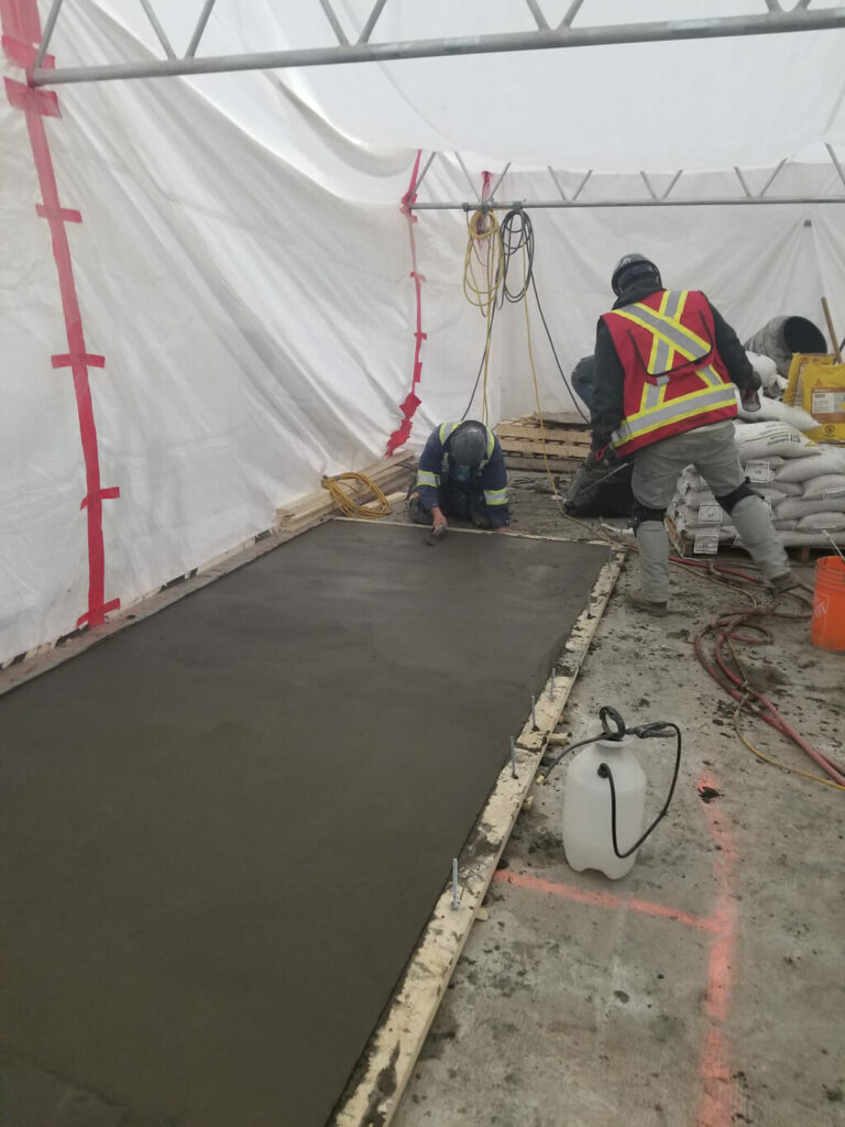 photo of ESS staff leveling fresh concrete in an Edmonton warehouse